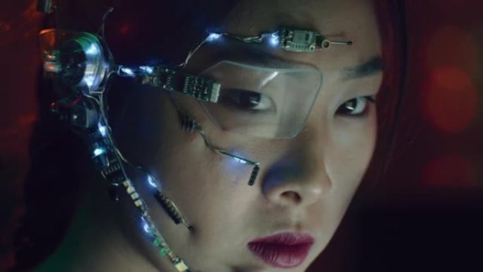 专注于赛博朋克服装和未来派眼镜的亚洲女孩在电脑上工作