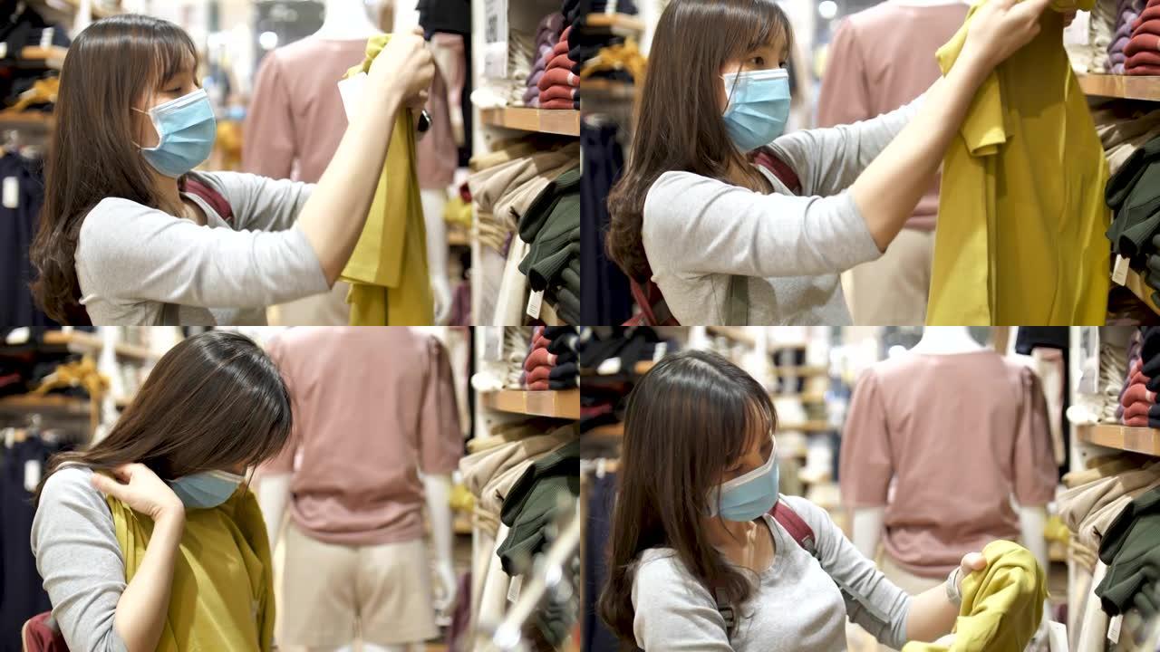 戴着医用口罩和手套的年轻女子在购物时选择新衣服