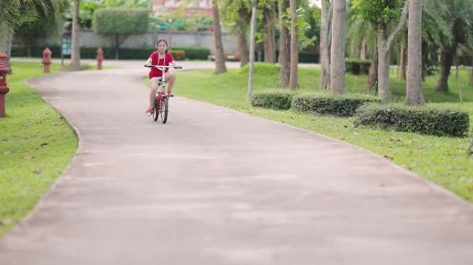 快乐亚洲女孩骑自行车在公园