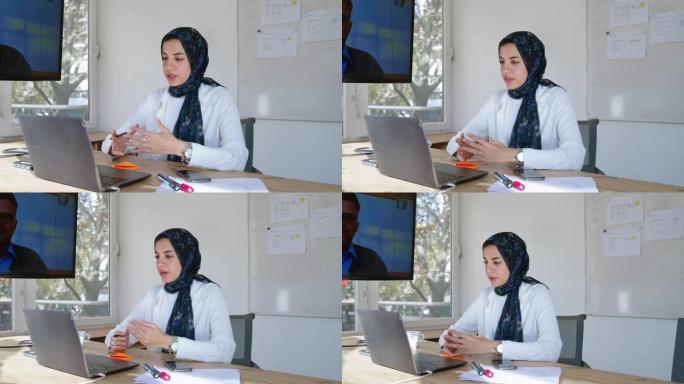 戴着头巾的中东妇女与笔记本电脑上的男同事进行视频通话