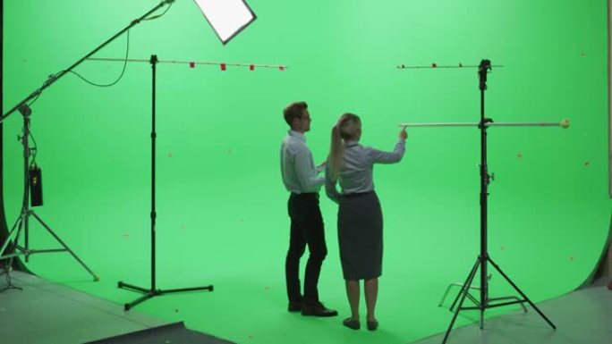 男女同事穿着便服，背站着-在绿色屏幕上使用笔记本电脑模拟色键工作室。商业，企业办公室，工作，技术概念