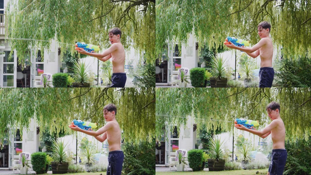 穿着游泳衣的男孩在夏天的花园里用水枪玩得开心