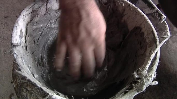 在贝尔工厂用泥土在水桶上工作的人。特写。
