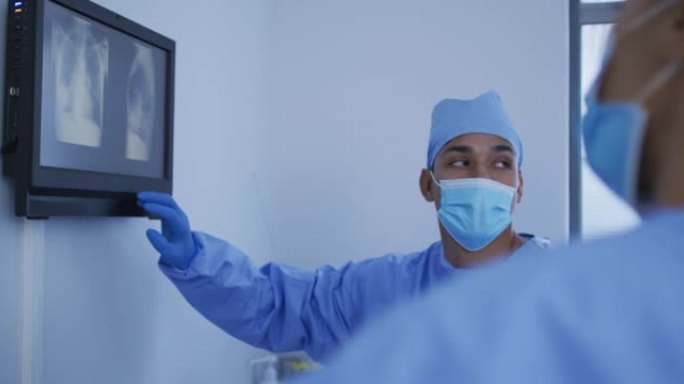 混血男外科医生穿着防护服，在屏幕上展示x射线