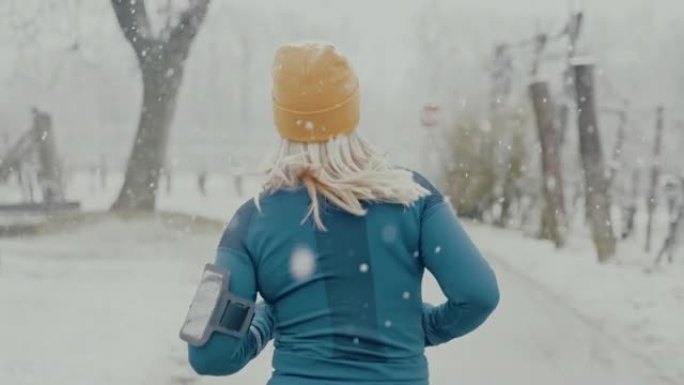 SLO MO女人在葡萄园的道路上在雪地里慢跑