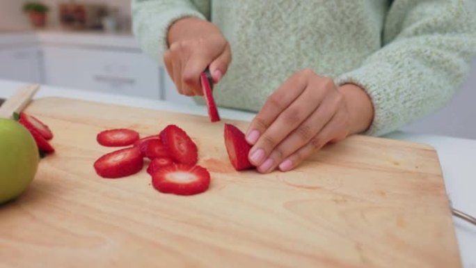 一名妇女在家里的厨房里切草莓，手，水果和饮食用刀子。食物，健康和营养，女性在房子的砧板上切成草莓