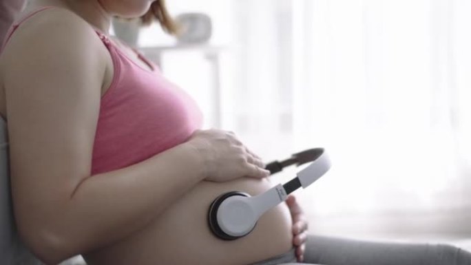 孕妇在家放松，肚子上戴着耳机听音乐，为宝宝播放音乐