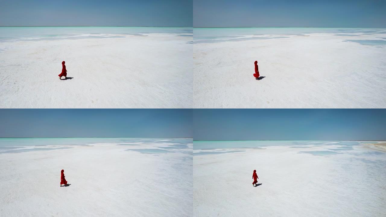 穿着红色连衣裙走在盐湖上的女人的鸟瞰图