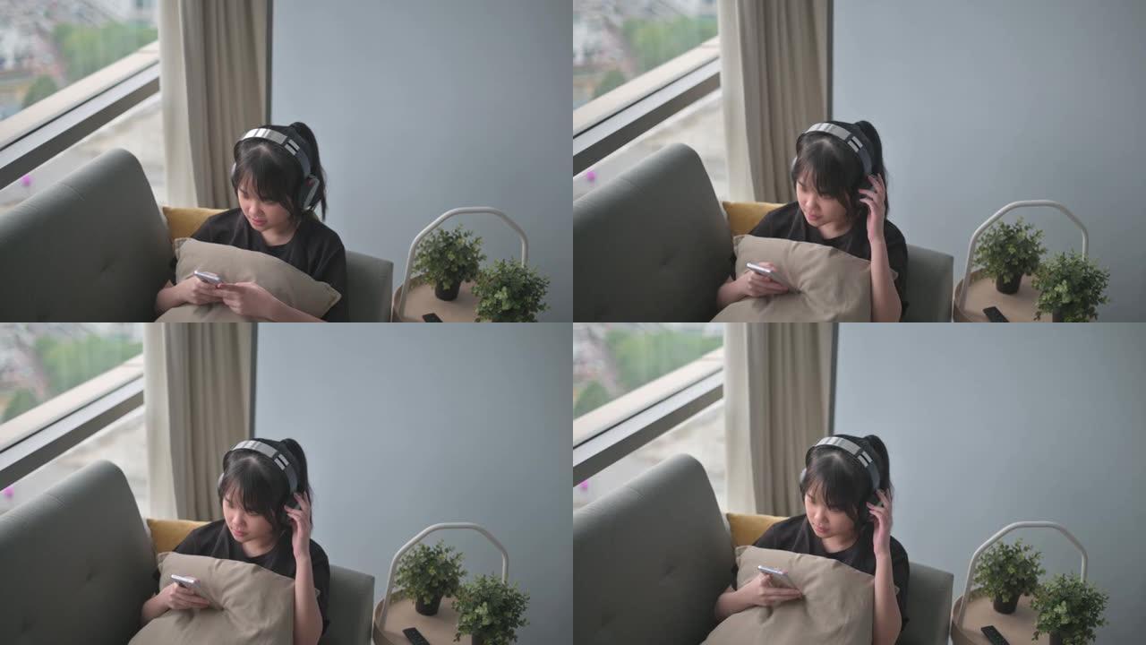 亚洲中国少女用耳机和智能手机躺在垫子上听音乐
