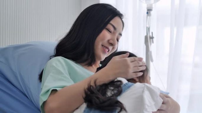 6-7岁的亚洲年轻女孩在医院的病床上与母亲拥抱。母亲和小女孩一起在诊所度过时光。单亲家庭