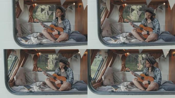 年轻女子在露营车中演奏夏威夷四弦琴