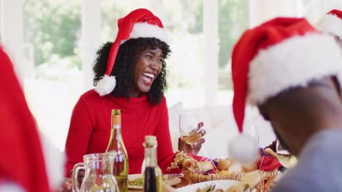 戴着圣诞老人帽子的非裔美国高级男子和年轻女子坐在dinin上说话和微笑