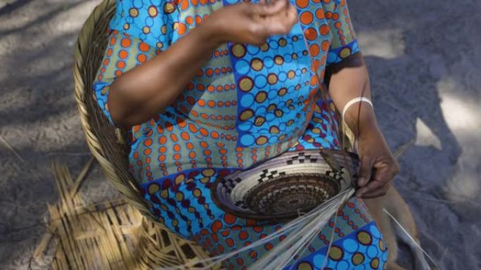 一名妇女编织由扇叶纤维制成的传统篮子的特写裁剪视图