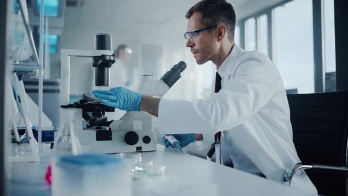 医学发展实验室: 白人男性科学家在显微镜下观察，分析培养皿样本。从事医学，生物技术研究的高级科学实验