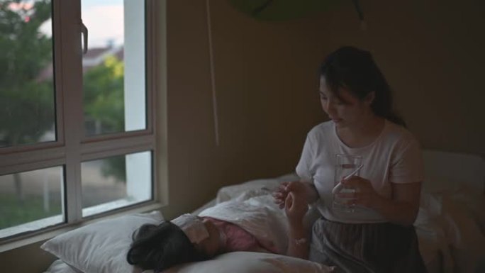 亚裔华裔妈妈在床上照顾女儿，用温度计测量体温