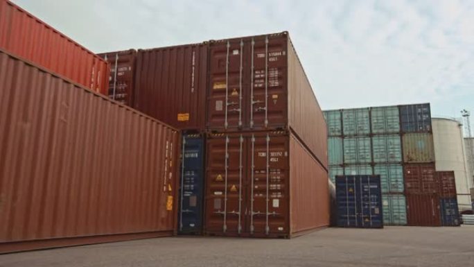 船厂物流运营中心的工业码头位置的低角度广角概览镜头，其中装有红色和蓝色钢制集装箱。白天多云的户外镜头