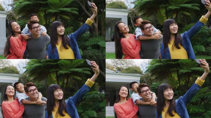 快乐的亚洲女儿与快乐的母亲和父亲piggybacking兄弟在花园里自拍