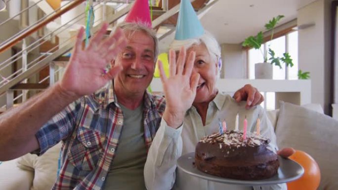 白人高级夫妇拿着蛋糕庆祝生日挥舞着相机的肖像