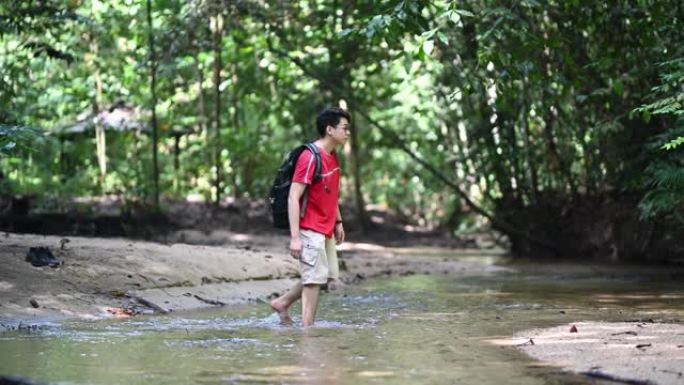 一名亚洲华裔年轻人丛林徒步穿越河流