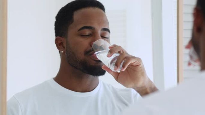 年轻昏昏欲睡的非洲裔男子喝纯净的新鲜矿泉水。
