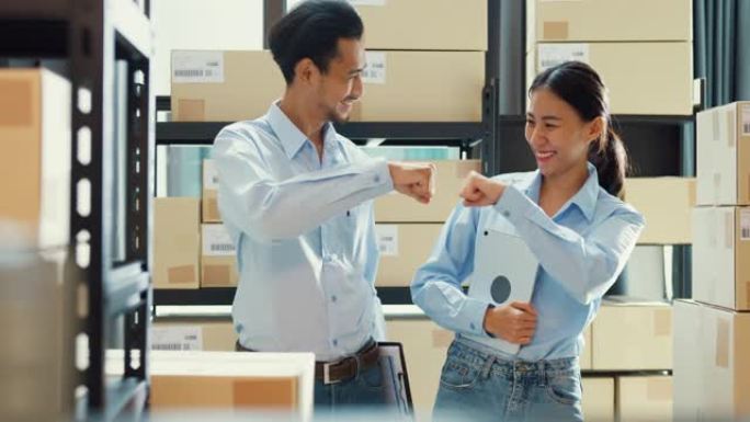 两个快乐的亚洲商业成功伙伴关系男女穿着制服衬衫携带数码平板电脑微笑看着仓库的相机。良好的合作效果，创