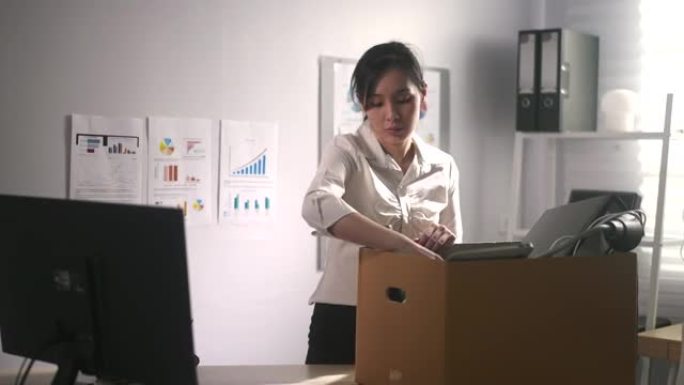 一家公司缩小规模后，亚洲妇女拿着盒子和办公室的东西