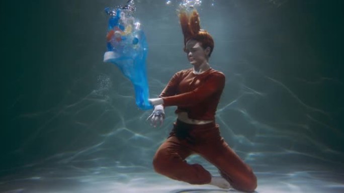 电影拍摄的年轻女子潜水扔掉垃圾袋，各种塑料废物漂浮在水下慢动作。