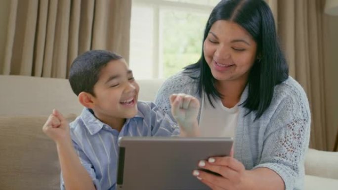 4k视频片段，一个可爱的小男孩用数字平板电脑和他的母亲在家里的沙发上