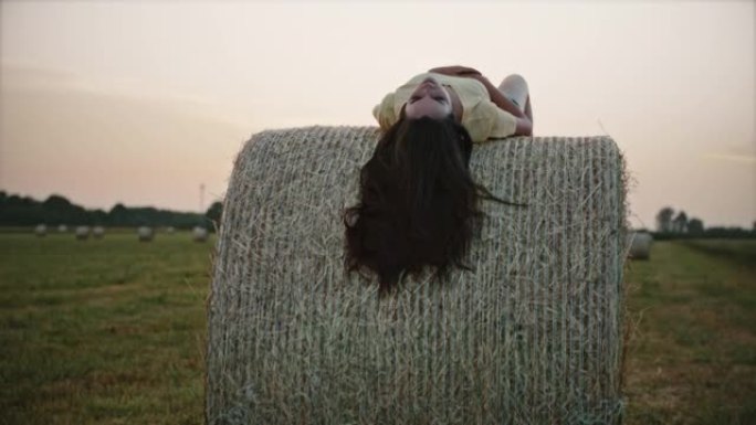 SLO MO年轻女子躺在一捆干草上