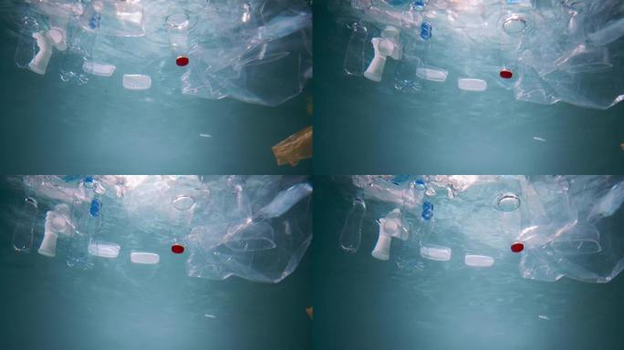 塑料包装废料。在美丽的太阳光线慢动作中漂浮在水下的各种垃圾的电影视图。