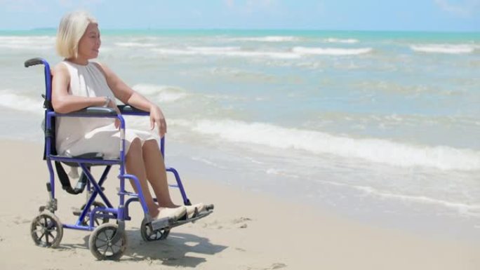 海滩上孤独的残疾坐在轮椅上看着海滩
