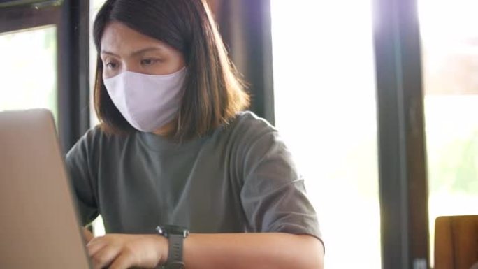 冠状病毒新型冠状病毒肺炎传播期间戴着口罩在家工作的年轻女子