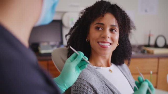 一名妇女在预约牙医时与牙医交谈。快乐的女性患者美丽的牙齿和灿烂的笑容在口腔检查。接受牙齿保健清洁及美