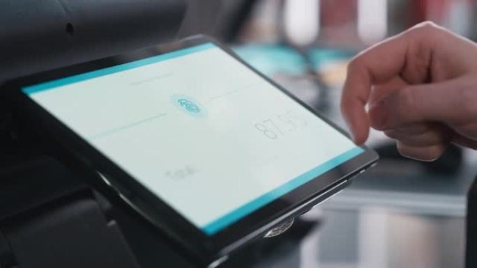 特写一个人触摸数字屏幕上的电子指纹识别功能的镜头，以便在服装店购物。客户在商店购买带有数字ID的商品
