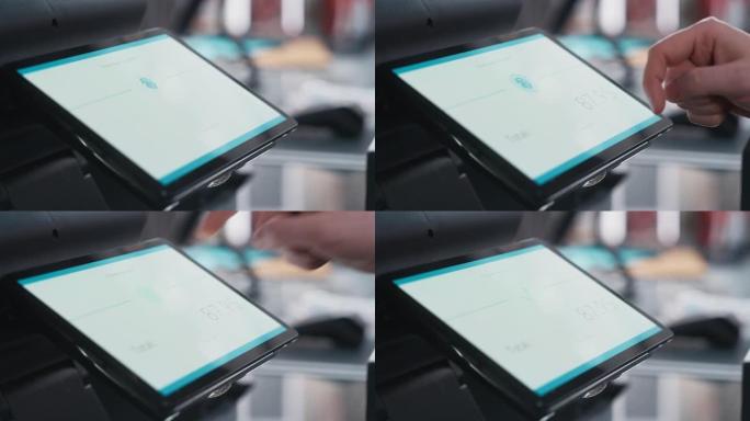 特写一个人触摸数字屏幕上的电子指纹识别功能的镜头，以便在服装店购物。客户在商店购买带有数字ID的商品