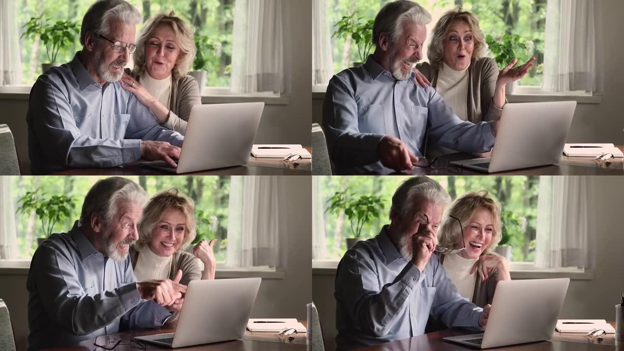 使用笔记本电脑阅读电子邮件庆祝的老年夫妇获得了巨大的机会