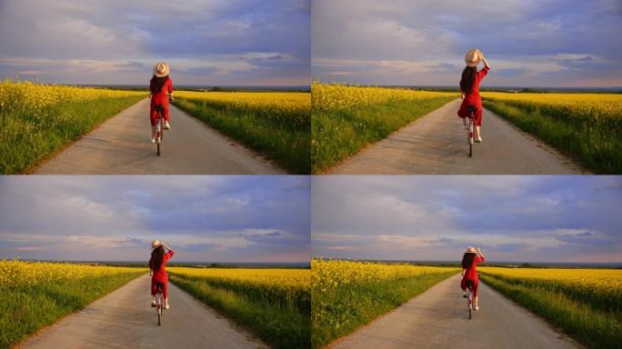 跟踪镜头中，一位穿着红色连衣裙的黑发女子骑着自行车穿过一片充满活力的黄色金鱼花，她举起了米色的帽子，