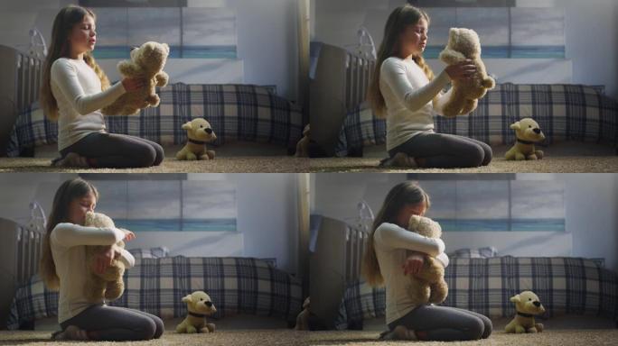 可爱的小女孩的电影镜头正在向她的泰迪熊讲述一个神奇的童话故事，并坐在托儿所舒适的地毯上拥抱它。爱情、