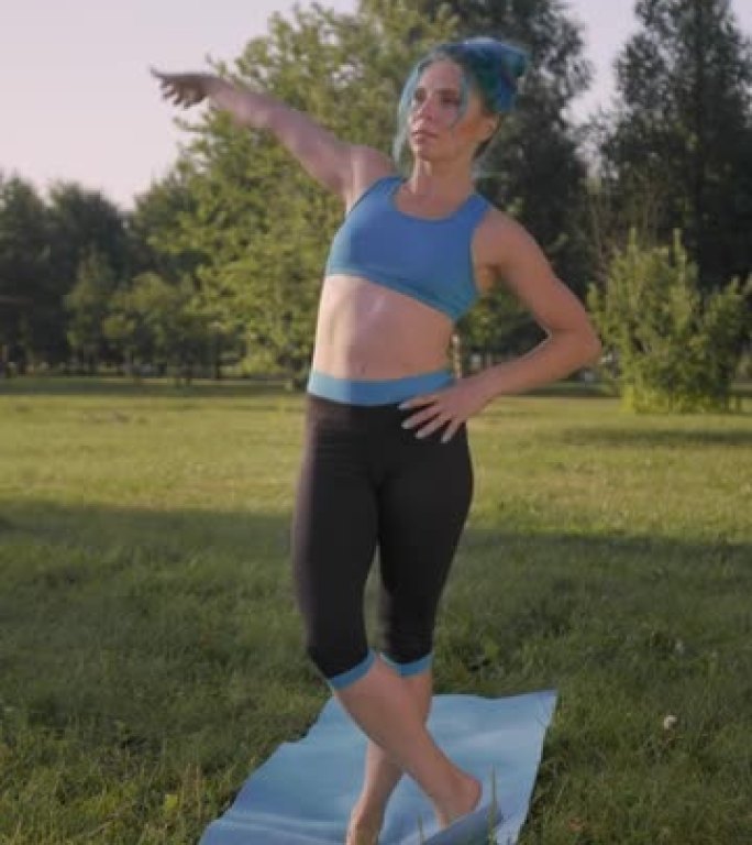 垂直视频，一位迷人的健身瑜伽老师穿着绿松石的头发，穿着绿松石的瑜伽服装，她做namaste站在一条腿