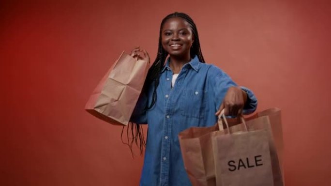 一位年轻的黑皮肤博客作者展示了她的购物袋，享受着成功的销售购物