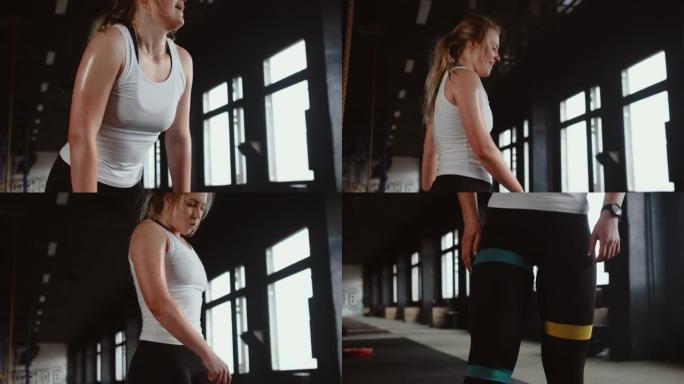 在健身房激烈锻炼后，电影般的倾斜在快乐美丽的年轻金发女运动员身上汗流浃背。
