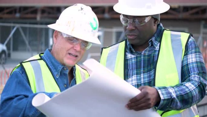 两名多种族建筑工人正在研究计划
