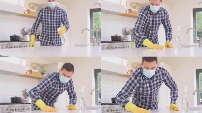 男人在家戴着口罩在厨房做家务，用喷雾清洁柜台表面