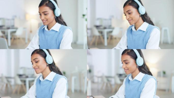 时髦的年轻女商人戴着耳机在笔记本电脑上工作时听音乐。现代创意数字实习生享受音频播放列表，以保持工作的