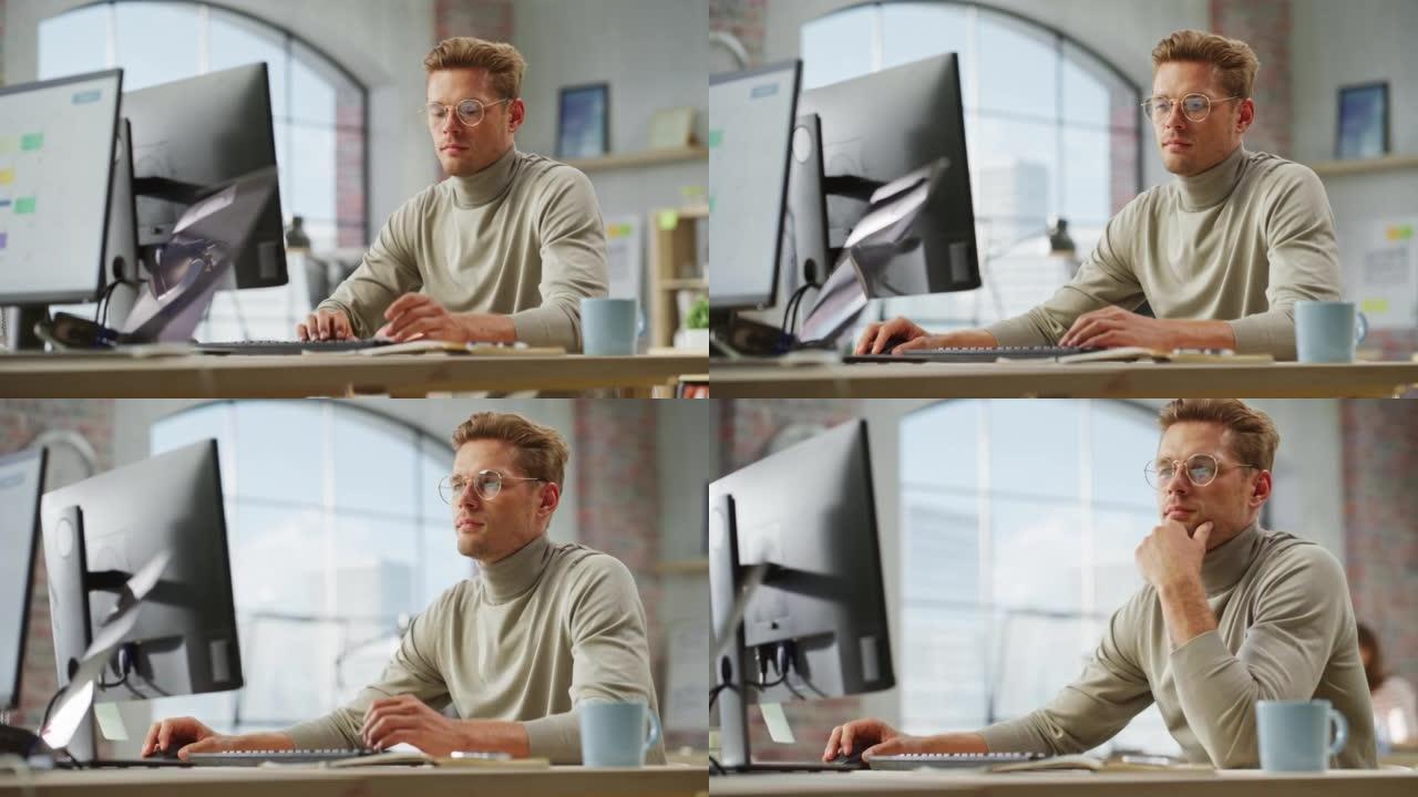 白天，在宽敞的现代办公室里，戴着眼镜的白人创意年轻人的肖像在电脑上工作。男平面设计师在开发新的视觉概