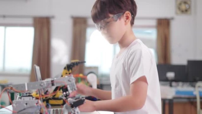 A schoolboy programming a robot on his laptop