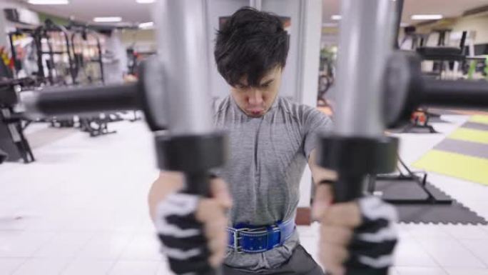 亚洲男子在健身房坐胸部按压锻炼。