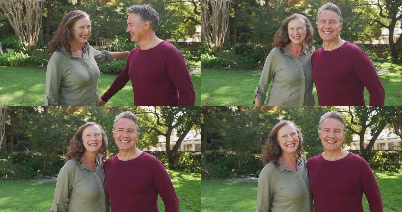 站在花园里拥抱和微笑的快乐高级高加索夫妇的肖像