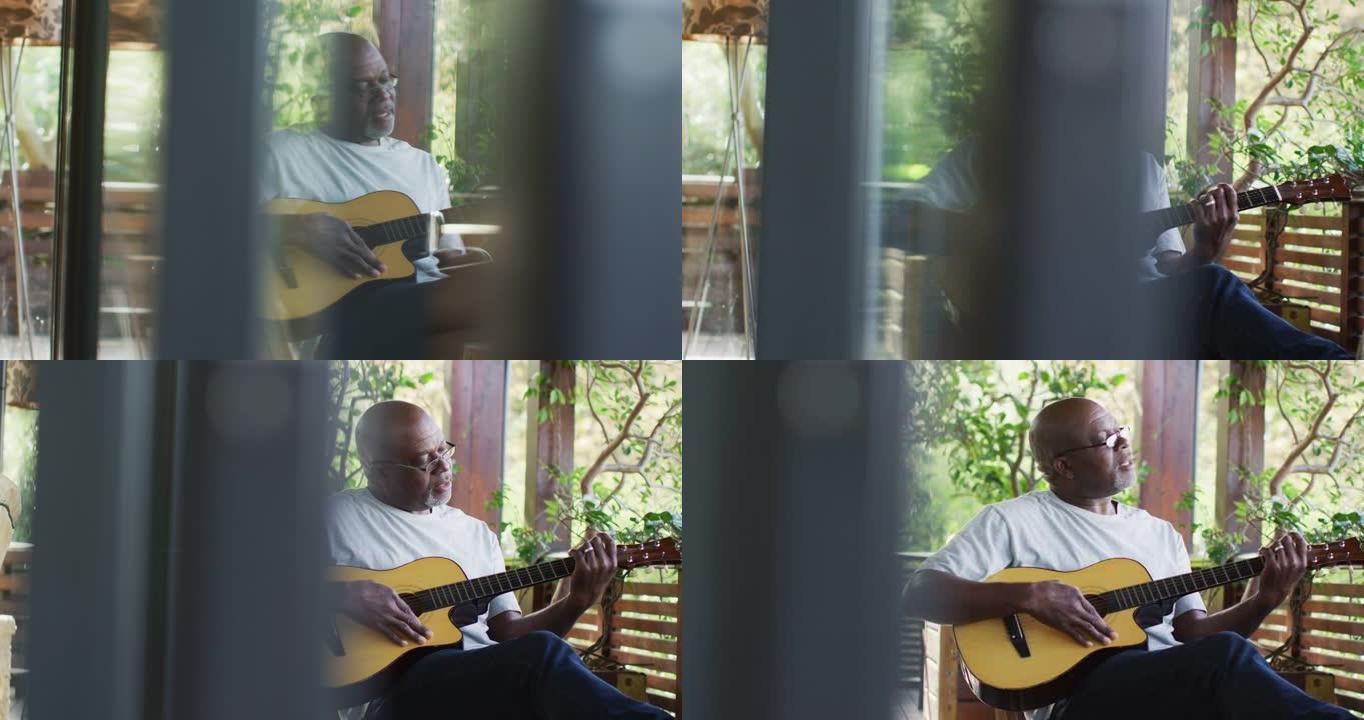体贴的非洲裔美国老人坐在阳台上弹奏原声吉他