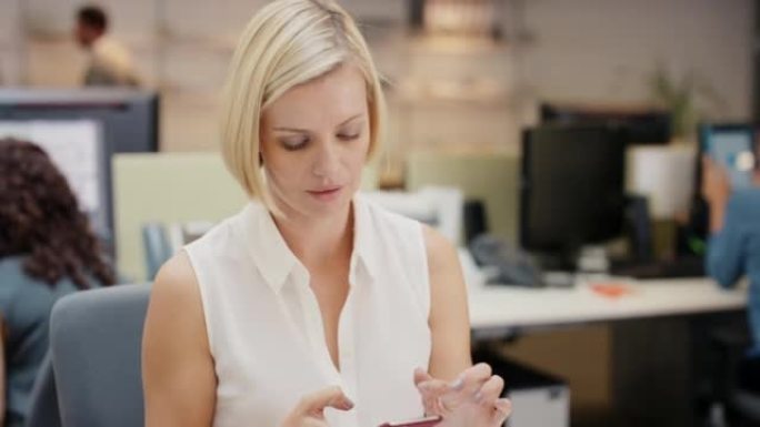 4k视频片段，一位迷人的年轻女商人坐在办公室并使用技术